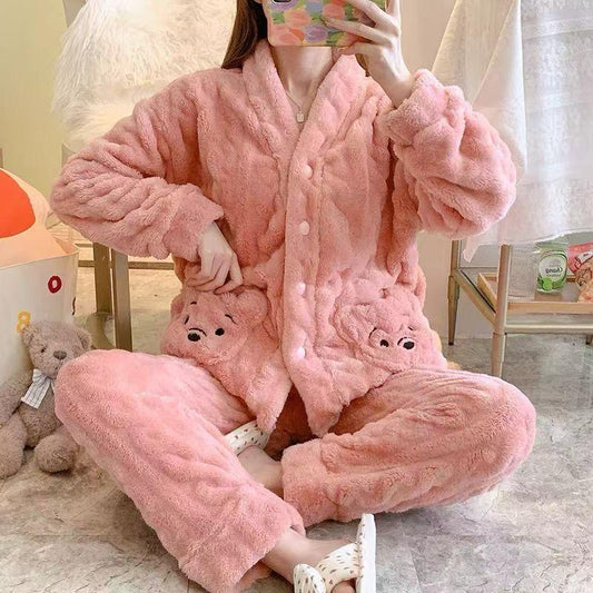 Person wearing a pink plush pajama set with teddy bear design in a room.