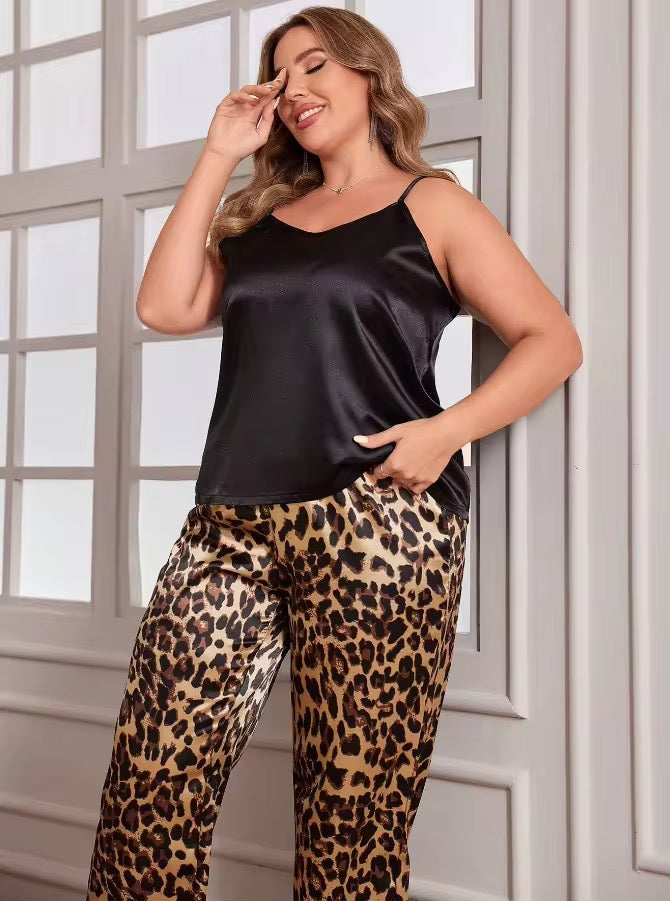 Woman wearing a black satin top and leopard print pants in front of a window.