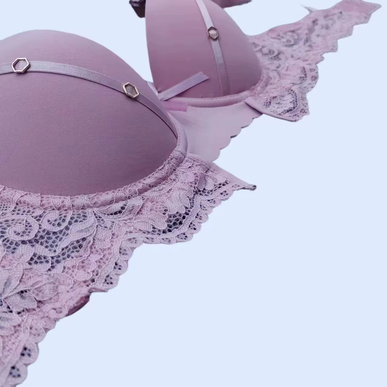 Pink lace bra and panties set on a light purple background