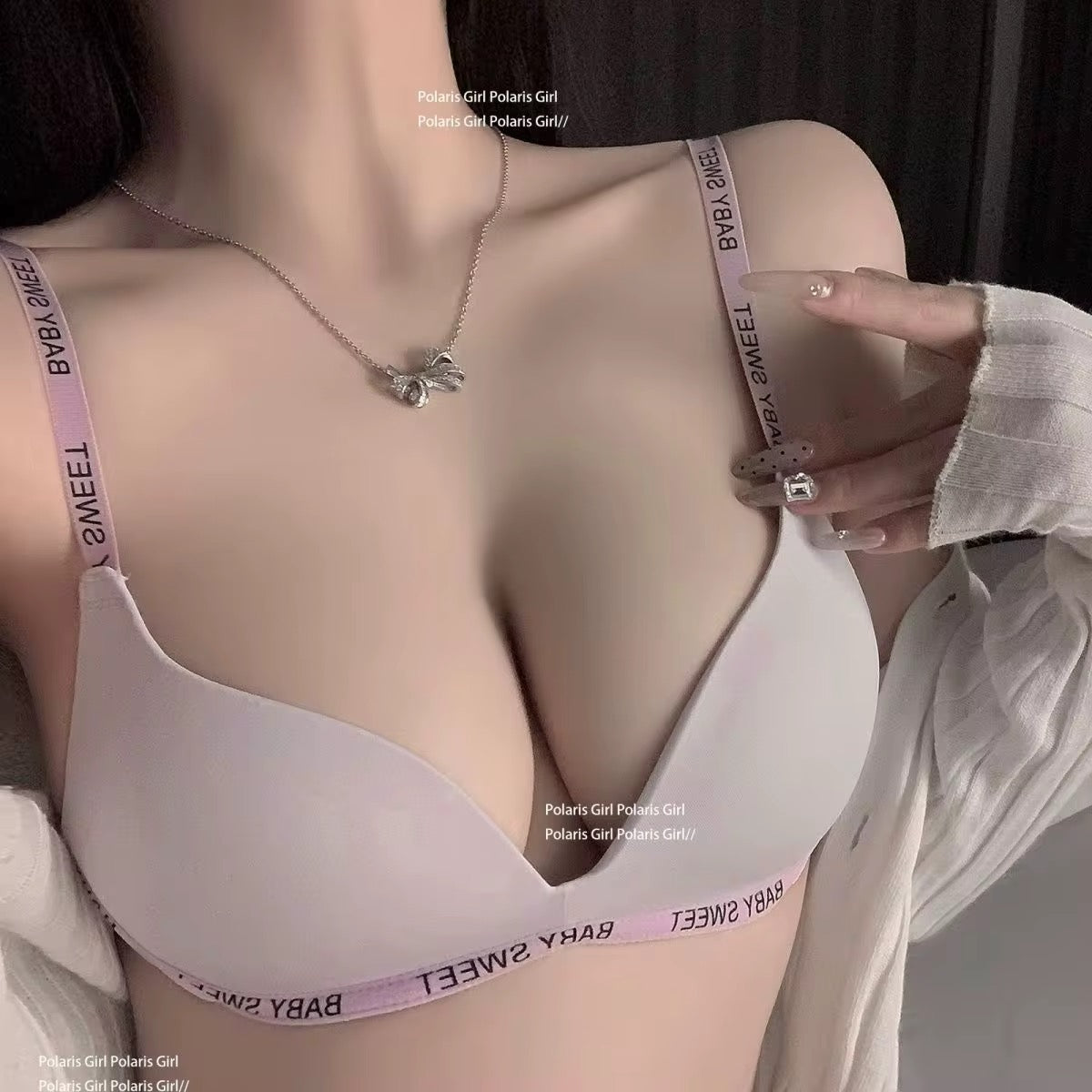 Person wearing a light-colored bra with visible branding, holding a phone.