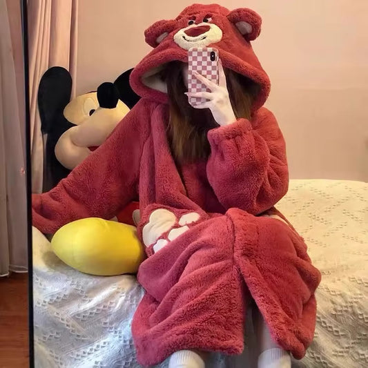 Person wearing a red plush bear robe sitting on a bed with a checkered phone case.