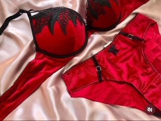 Red lingerie set with black lace details on a beige fabric background