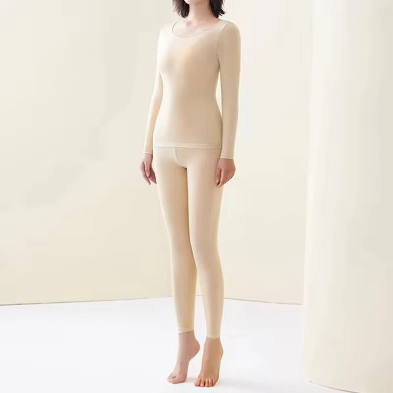 Person wearing a beige long-sleeve top and leggings against a plain background