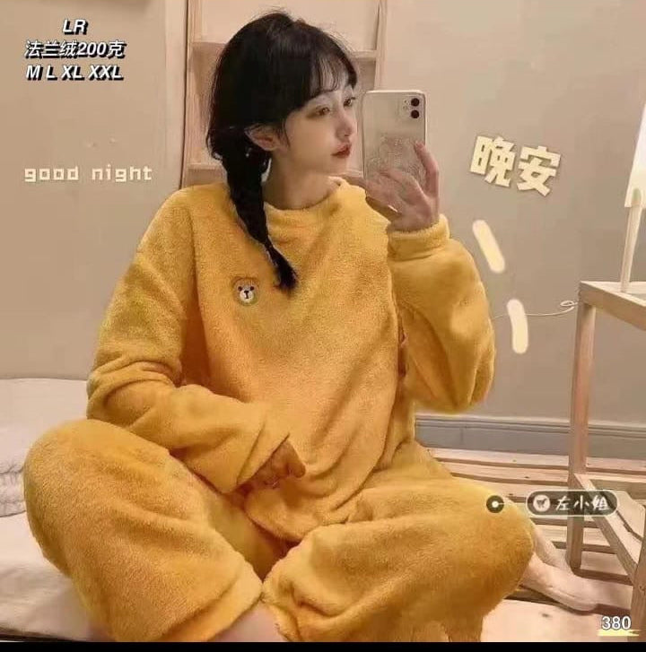 Person wearing yellow pajamas taking a mirror selfie in a room with text on the wall.