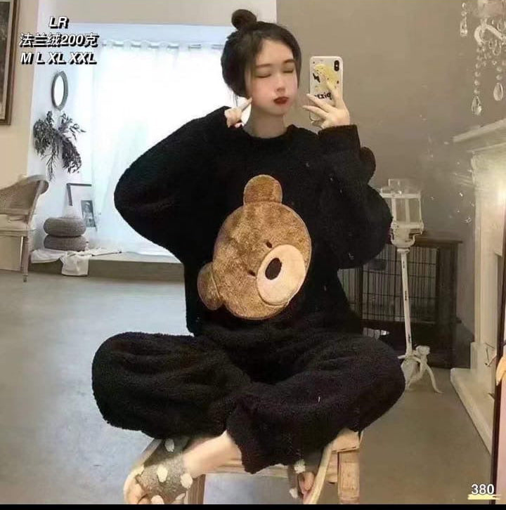 Person wearing a black sweater with a bear design in a room.