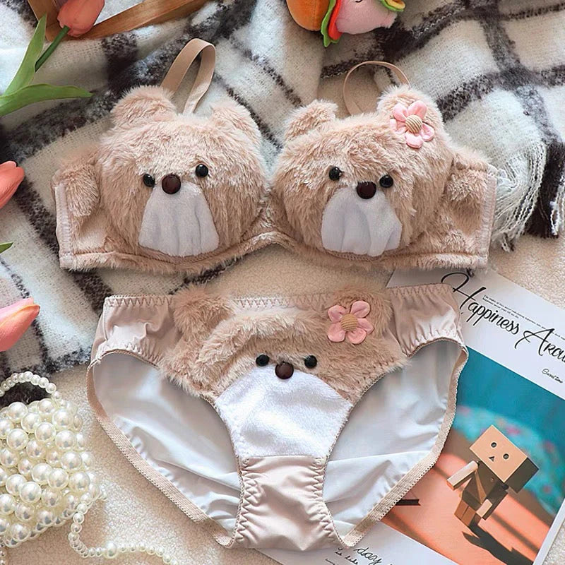 Two teddy bear-shaped baby rompers on a checkered blanket with a magazine underneath.