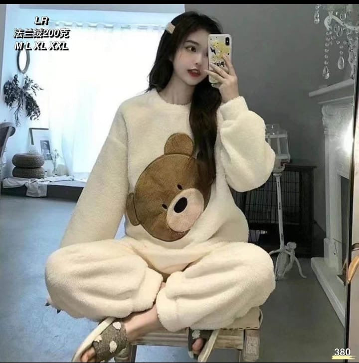 Person wearing a white sweater with a bear design sitting on a chair.