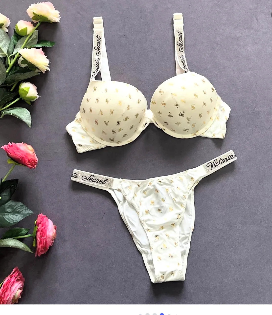 Victoria's Secret bra and panties set on a dark surface with flowers around.