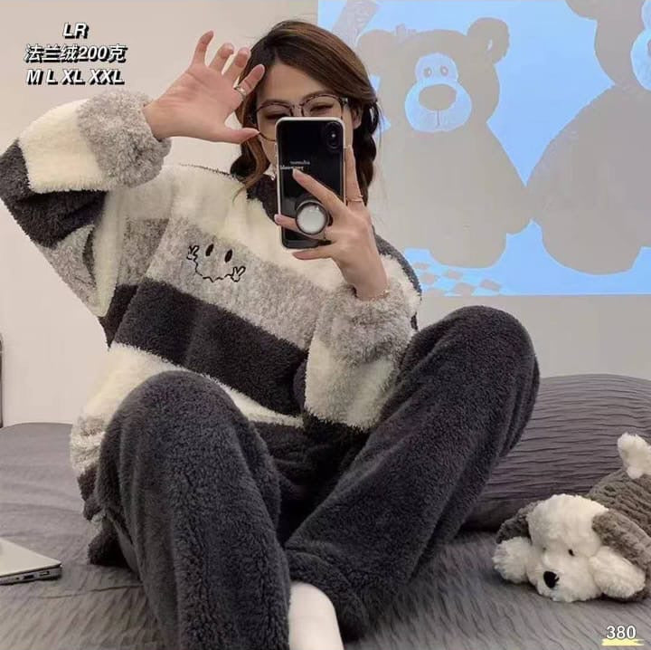 Person wearing a striped sweater sitting on a couch with a teddy bear, taking a mirror selfie.