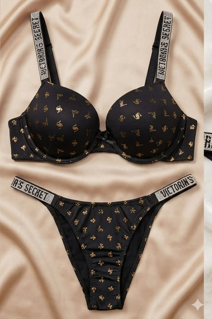 Victoria's Secret black patterned bra and panties set on a beige fabric background