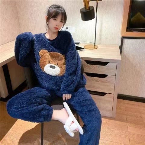 Person wearing a blue fleece onesie with a bear face design, sitting in a room.