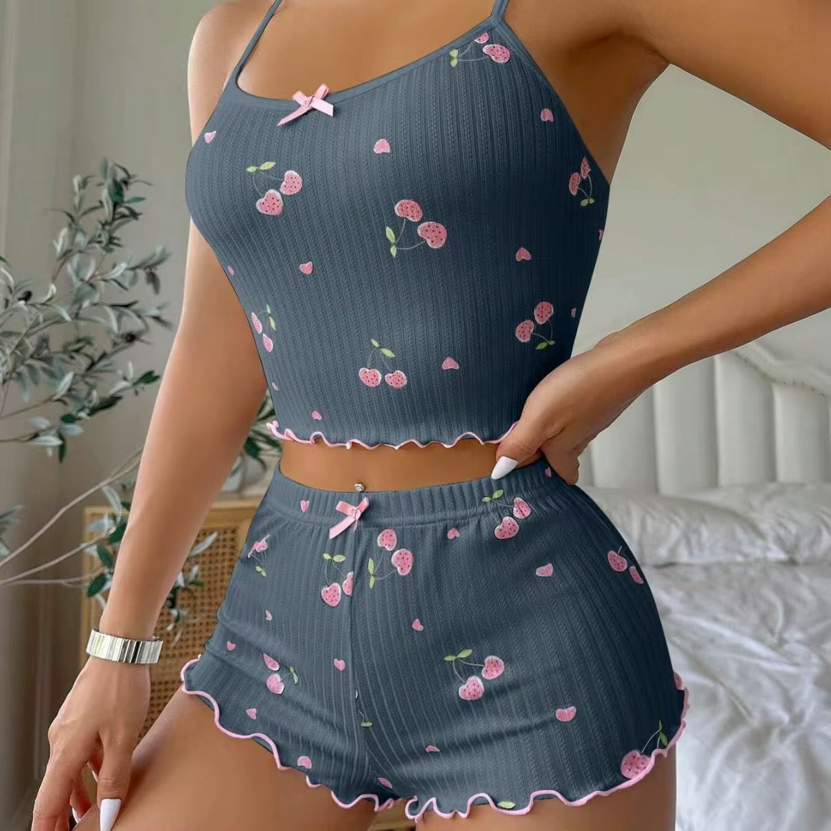 Woman wearing a navy blue pajama set with pink floral patterns in a bedroom setting.
