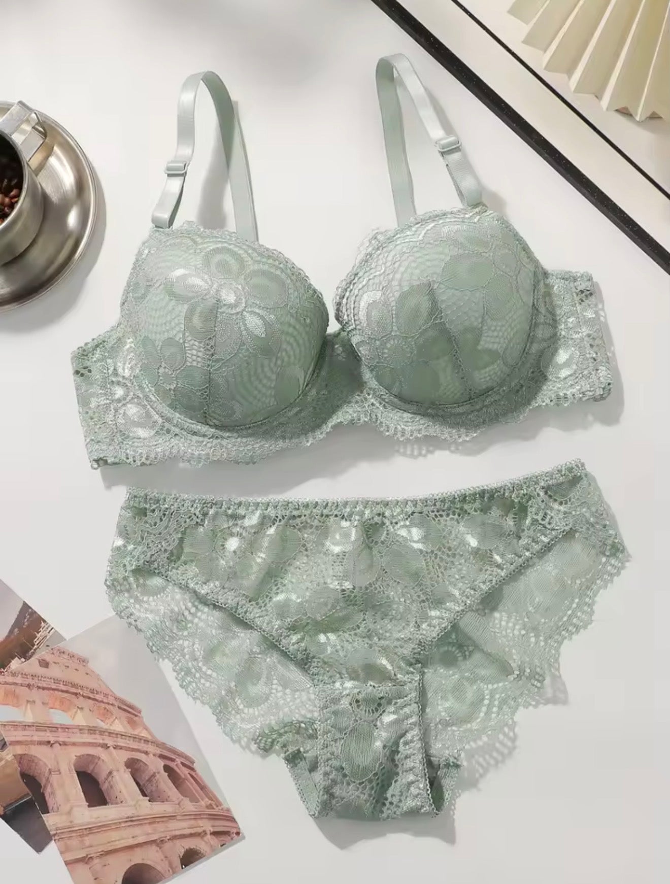Set of light green lace lingerie on a white surface with architectural magazine in the background