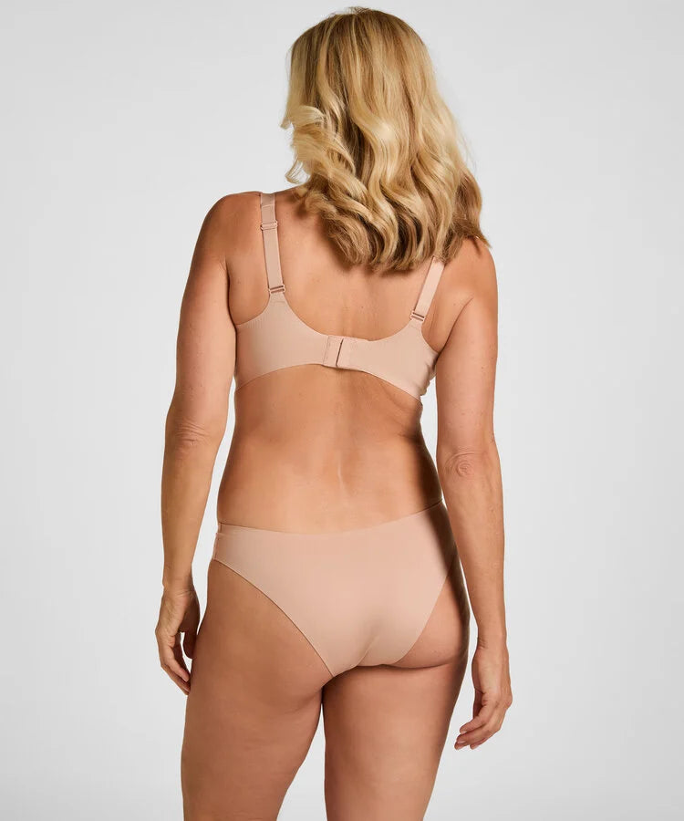 A woman shown from the back wearing a matching nude-beige bra and underwear set against a light gray studio background.