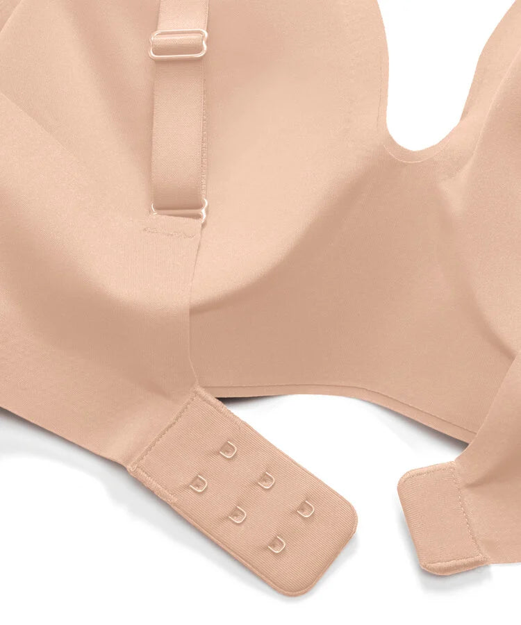Close-up of a seamless, nude-beige wireless bra showing the adjustable underband with six hook-and-eye closures and the shoulder strap.