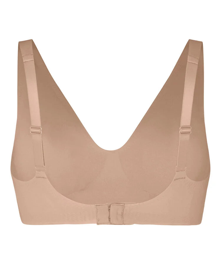 A seamless, wireless bra in a nude beige color, featuring wide adjustable shoulder straps and a center gore with a small buckle closure, shown against a plain white background.