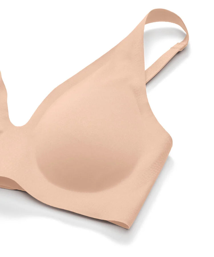 A seamless, molded-cup bra in a light peach-beige shade, shown from a three-quarters perspective on a clean white background.