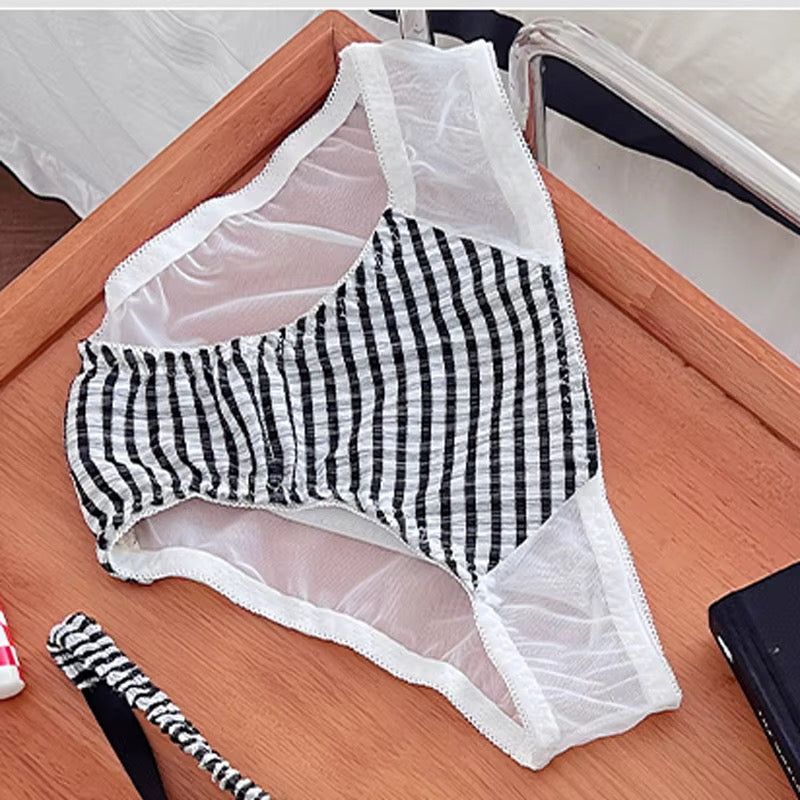 Black and white gingham checkered underwear with white mesh side panels and lace trim, laid flat on a wooden surface.