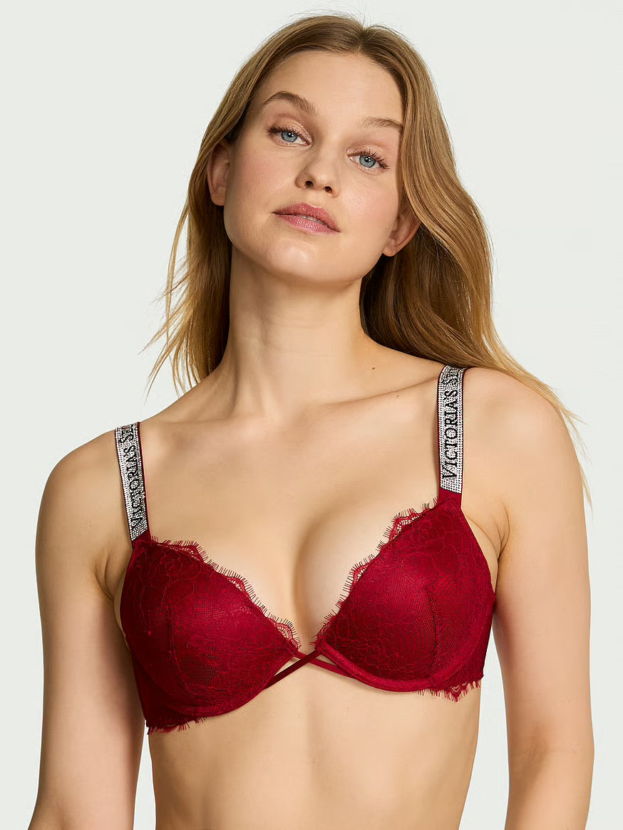A woman wearing a Victoria's Secret deep red lace underwire bra with patterned shoulder straps, shown against a light gray studio background.