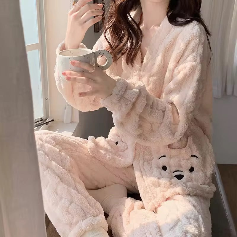 Person wearing a fluffy pink robe with animal ears, sitting by a window holding a mug.