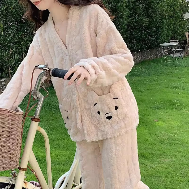 Person wearing a fluffy pink robe with a bear face design, standing next to a bicycle outdoors.