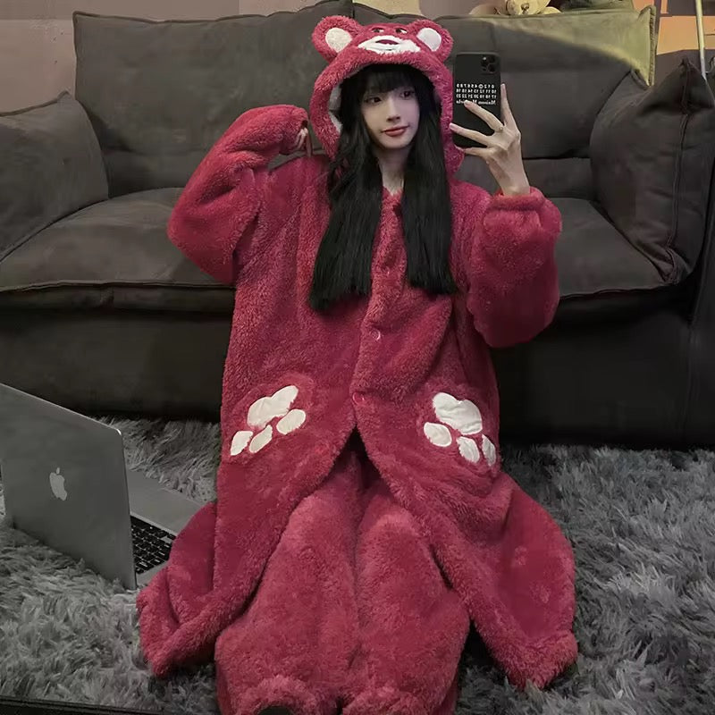 Person wearing a red bear-themed onesie sitting on the floor with a laptop and phone.