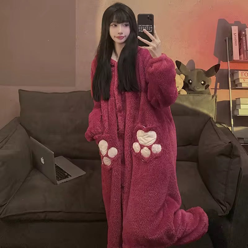 Person wearing a pink onesie with paw prints, taking a selfie in a room with a couch and a small dog figure.