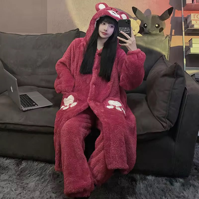 Person wearing a pink onesie with animal ears, sitting on a couch with a laptop and plush toys.