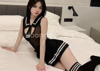 Woman in a black and white outfit sitting on a bed.