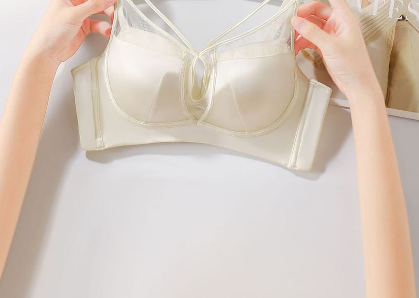 Beige bra held open by hands on a light gray background