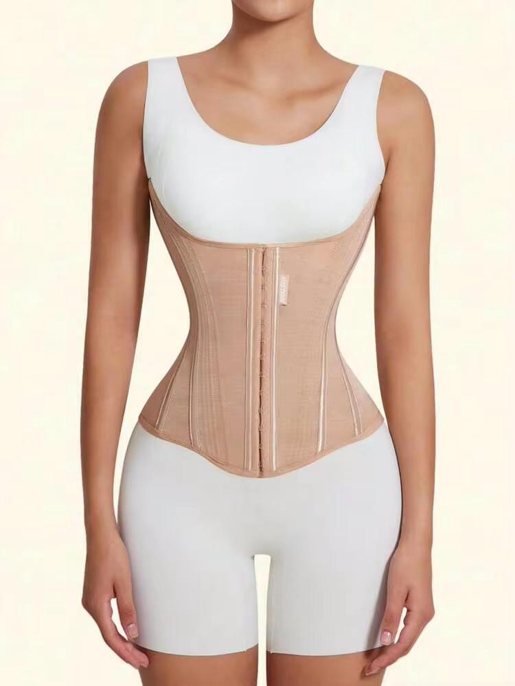 A model wearing a beige waist trainer corset with a front zipper, paired with white shorts, against a light beige background.