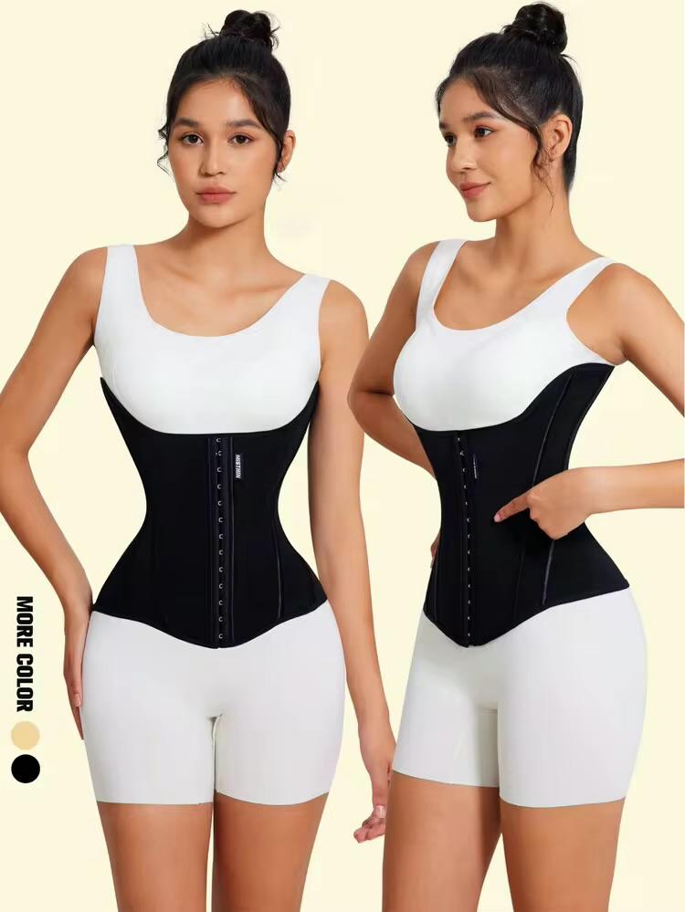 Two women modeling a black and white waist trainer corset with matching white shorts against a pale beige background. One model faces forward and the other faces sideways, pointing to the side of the corset.