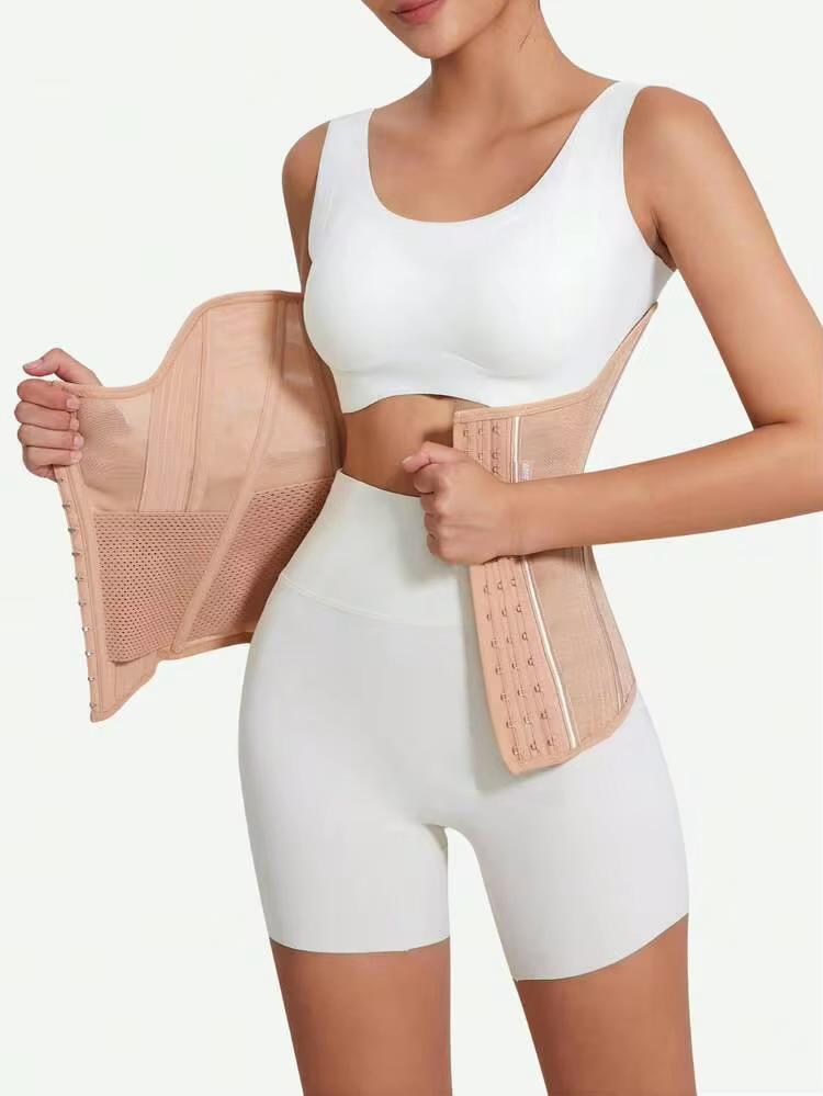 A woman modeling a beige waist trainer belt with built-in support panels, shown against a plain light background.